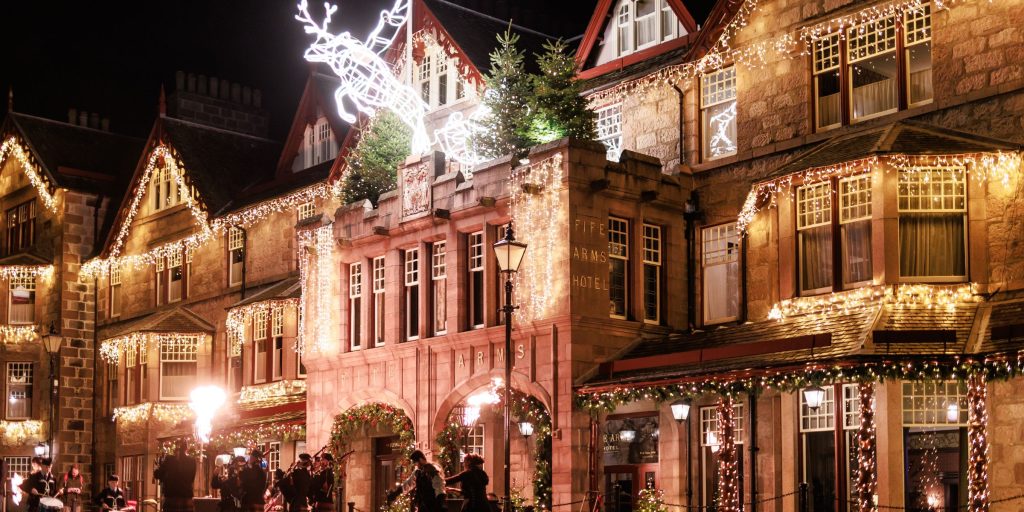 Exterior of Fife Arms hotel with festive lights and pipe band playing